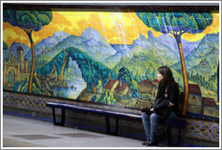 Young woman sitting in front of a mural called Paisajes de Espa?Mariano Moreno station, Subte (Buenos Aires subway).