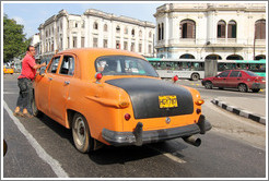 Driver beside his orange and black taxi, Avenida Salvador Allende (Carlos III).