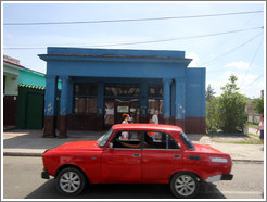 Red car in front of a blue building, Calzada 10 de Octubre.