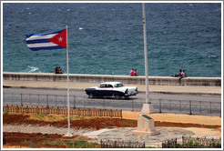 Cuban flag and a black and white car on the Malec&oacute;n.