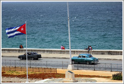 Cuban flag and black and blue cars on the Malec&oacute;n.
