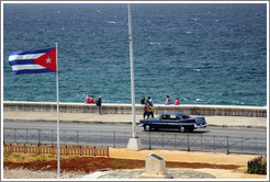 Cuban flag and a black car on the Malec&oacute;n.