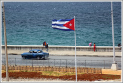 Cuban flag and a blue car on the Malec&oacute;n.
