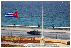 Cuban flag and a dark green car on the Malec&oacute;n.