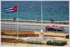 Cuban flag and a red convertible on the Malec&oacute;n.