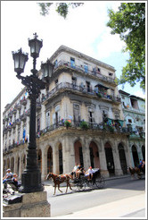 Horse drawn carriage passing a beige building, Paseo del Prado.