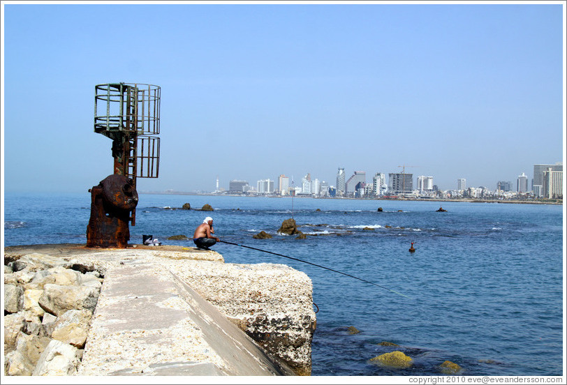 Man fishing, with Tel Aviv behind him.