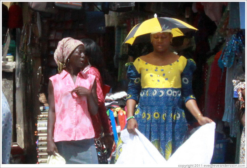 Two women talking. One wears an umbrella hat.