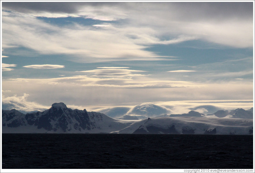 Lenticular clouds hovering over mountains on the west coast of Graham Land.