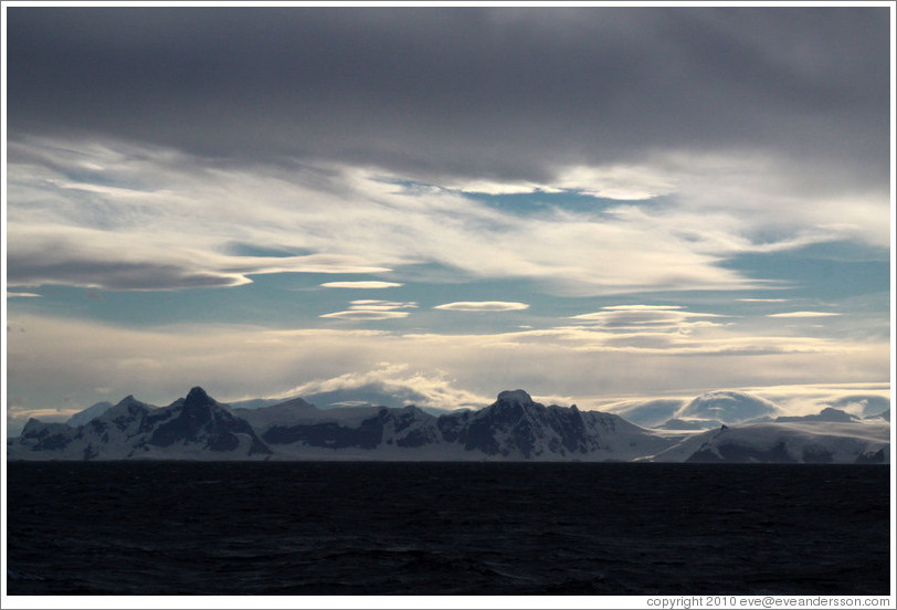 Lenticular clouds hovering over mountains on the west coast of Graham Land.