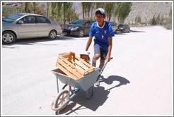 Boy pushing girl in wheelbarrow.