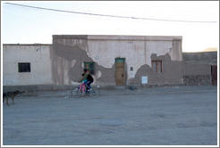 Two people riding a bicycle at dusk.