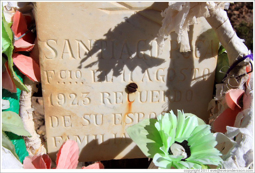 Headstone and plastic flowers for Santiago Ruca who passed away in August 1923, in a small miners' cemetery near La Polvorilla viaduct.