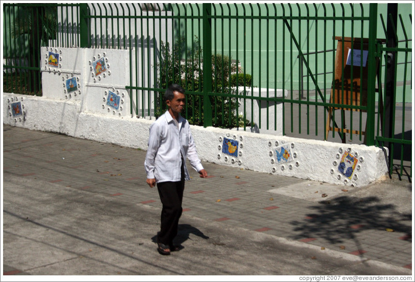 Man walking past tiled wall.