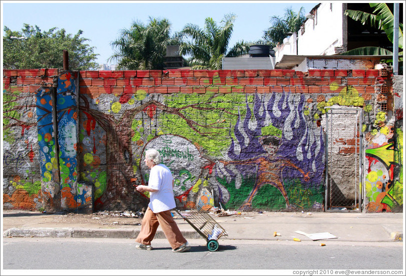 Graffiti: man with purple flames.  Woman walking in front.  Rua Nova Cidade.
