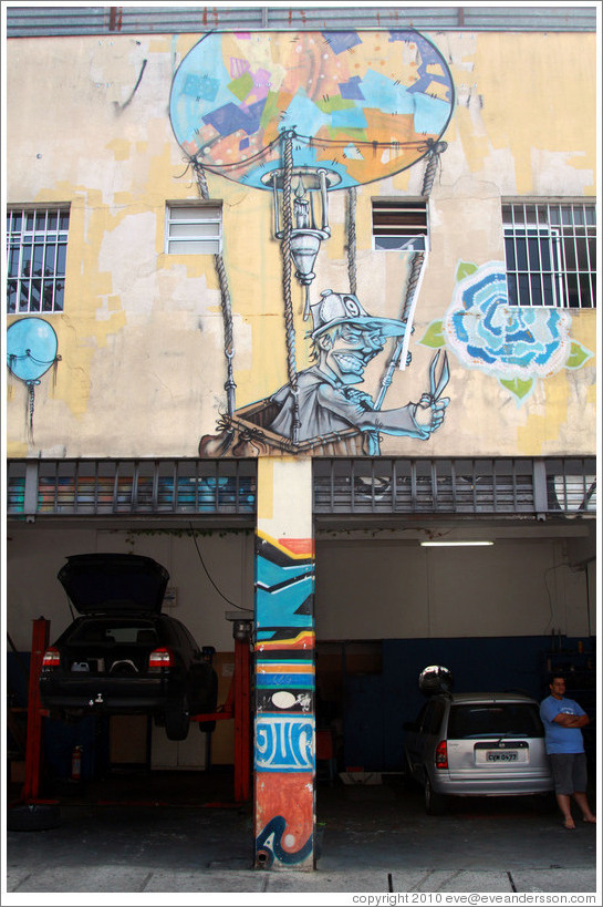 Graffiti over an auto mechanic: man with scissors in a hot air balloon.  Villa Magdalenda neighborhood.  Rua Belmiro Braga and Rua Cardeal Arcoverde.