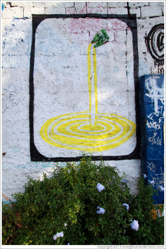 Graffiti: yellow liquid pouring out of two plastic bottles.  The bottles are real.  Villa Magdalenda neighborhood.  Playground on Rua Belmiro Braga.
