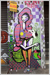 Graffiti: sitting woman with a hood, skirt, and striped socks, holding a bag.  Villa Magdalenda neighborhood.  Rua Cardeal Arcoverde.