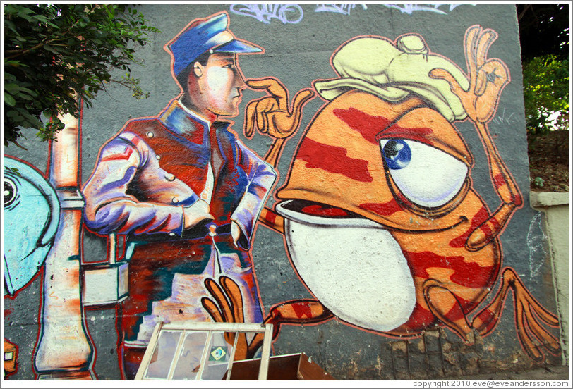 Graffiti: man and orange frog wearing a hat.  Villa Magdalenda neighborhood.  Rua Henrique Schaumann near Rua Cardeal Arcoverde.