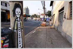 Graffiti: woman wearing a dress on lamppost.  Villa Magdalenda neighborhood.  Rua Padre Jo?Gon?ves and Rua In?o Pereira da Rocha.