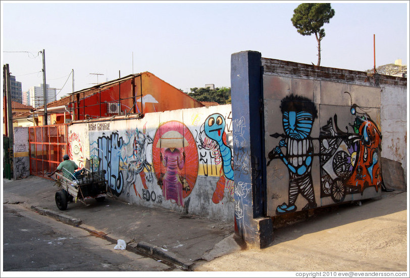 Man pulling a cart near graffiti of a man pulling a cart.  Villa Magdalenda neighborhood.  Rua Padre Jo?Gon?ves near Rua Fradique Coutinho.