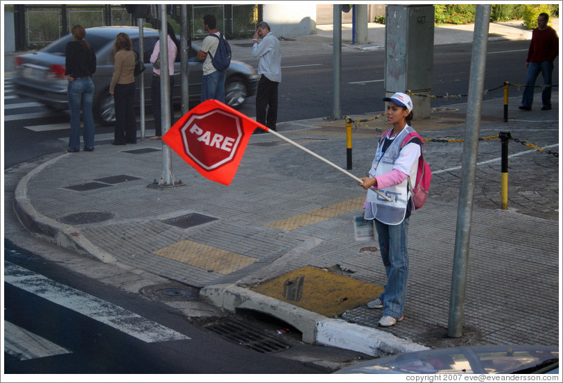 Woman holding PARE (STOP) sign.