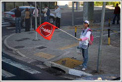 Woman holding PARE (STOP) sign.