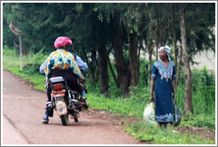 Man and woman on a motorcycle talking with a woman at the side of the road.