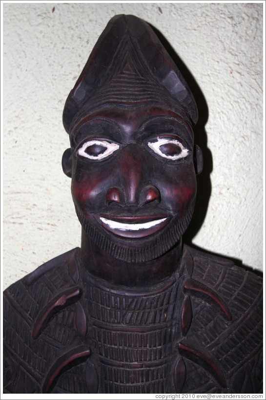 Wooden carving of a man with white eyes and smile.