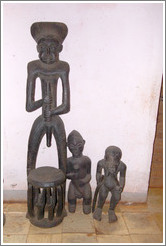 Chair with a wood carving of a man, and two wood carvings of smaller figures.