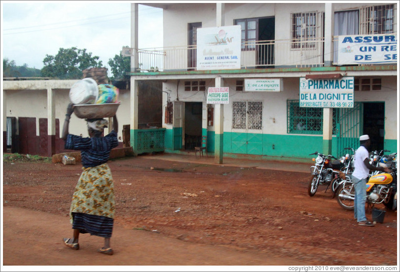 Woman carrying bowls on her head.