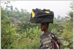 Woman carrying a duffel bag on her head.