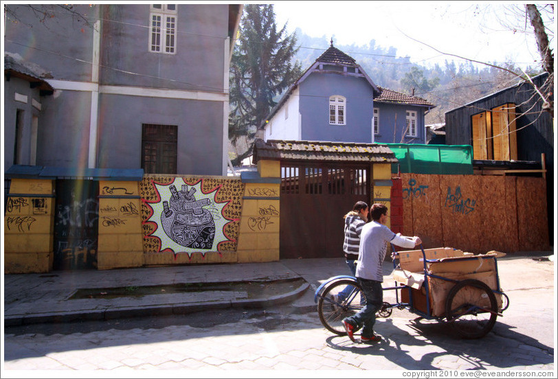 People pushing a cart in front of graffiti depicting a heart, Santa Filomena near Ernesto Pinto Lagarrigue.