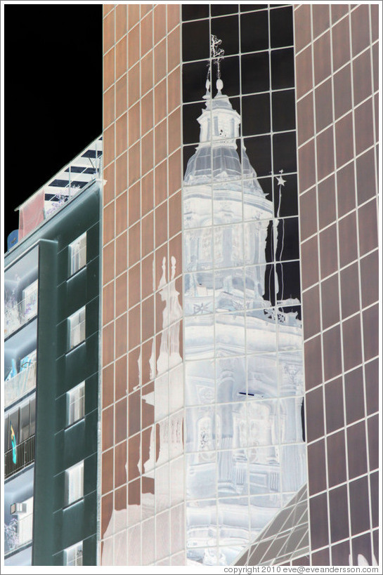 A tower of the Cathedral Metropolitana reflected in a modern building, Plaza de Armas.  The colors in this photo have been inverted.