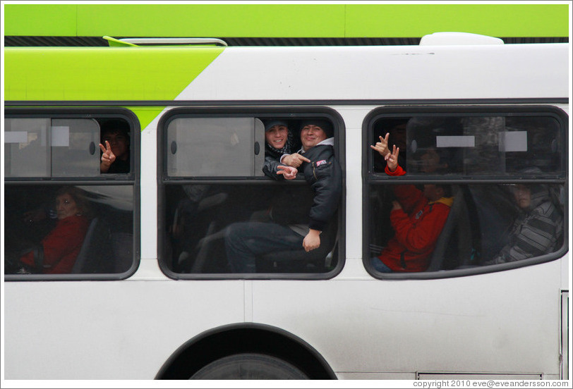 People on a bus making peace signs.
