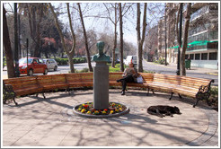 Man reading a newspaper on a bench, while a homeless dog sleeps near by.  Corner of Monjitas and Merced, Barrio Lastarria.