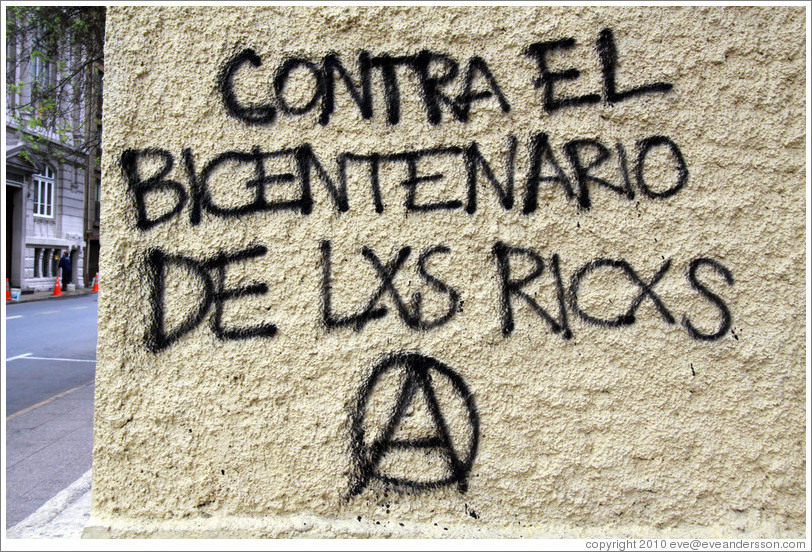 Graffiti: Contra el Bicentenario de Lxs Ricxs.  (Against the Bicentennial of the rich.)  For some reason, the Os have been replaced with Xs in "Los Ricos" in this and other graffiti in the city.  San Mart? city center.