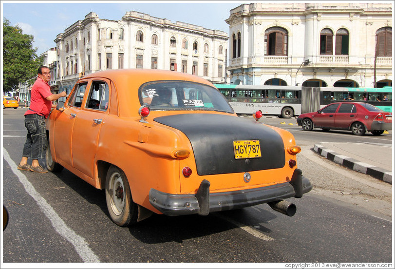 Driver beside his orange and black taxi, Avenida Salvador Allende (Carlos III).
