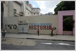 People walking past words painted on a wall saying "Fieles a nuestra historia" ("Faithful to our history"), Avenida Simon Bolivar (Calle Reina).