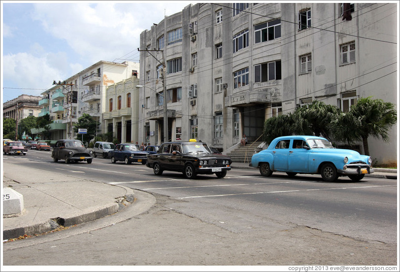 Blue car followed by black taxi, corner of 25th Street and L Street.