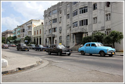 Blue car followed by black taxi, corner of 25th Street and L Street.