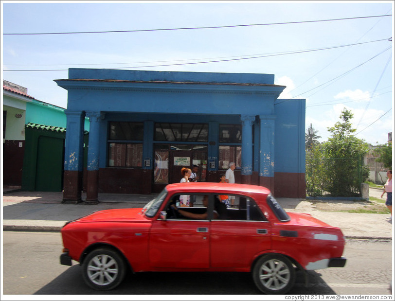 Red car in front of a blue building, Calzada 10 de Octubre.