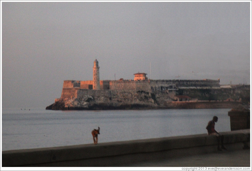 Morro Castle (Castillo de los Tres Reyes del Morro), with a dog standing on the Malec&oacute;n wall, at dusk.