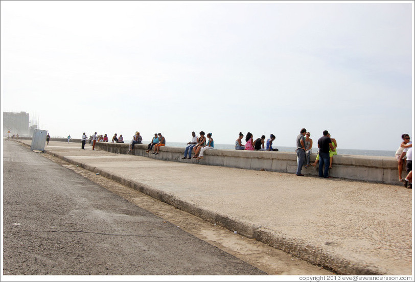 People sitting on the wall on the Malec&oacute;n.