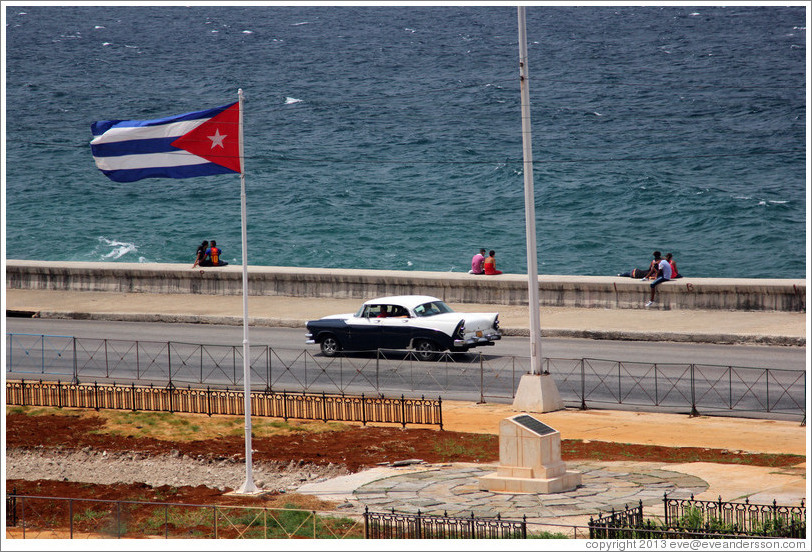 Cuban flag and a black and white car on the Malec&oacute;n.