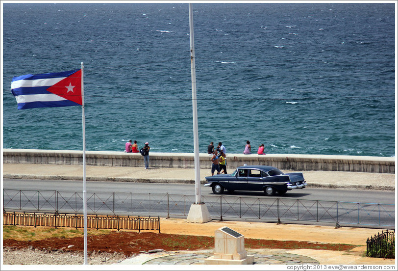 Cuban flag and a black car on the Malec&oacute;n.