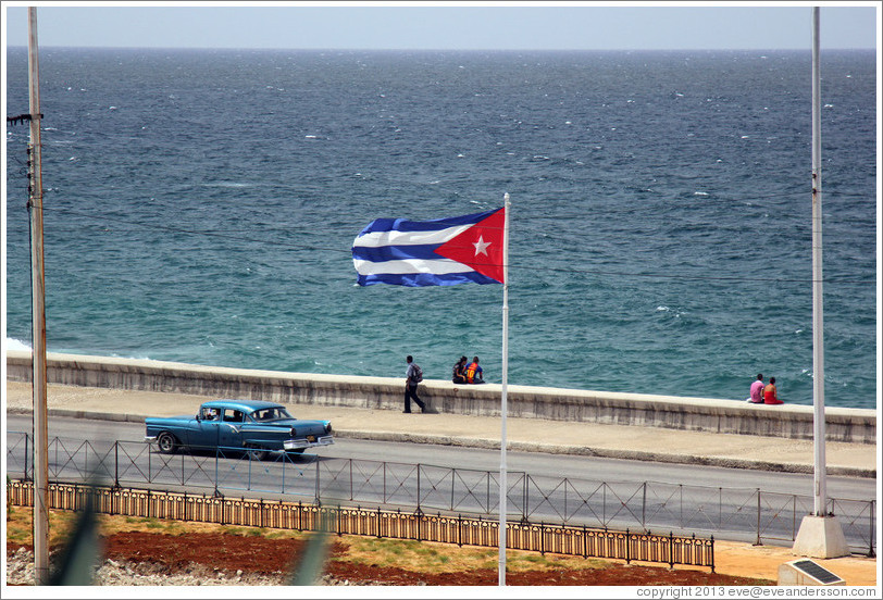 Cuban flag and a blue car on the Malec&oacute;n.