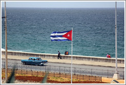 Cuban flag and a blue car on the Malec&oacute;n.
