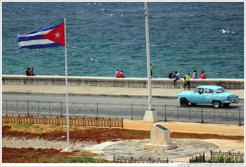 Cuban flag and a blue car on the Malec&oacute;n.