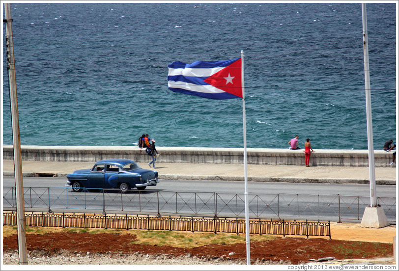 Cuban flag and a blue car on the Malec&oacute;n.